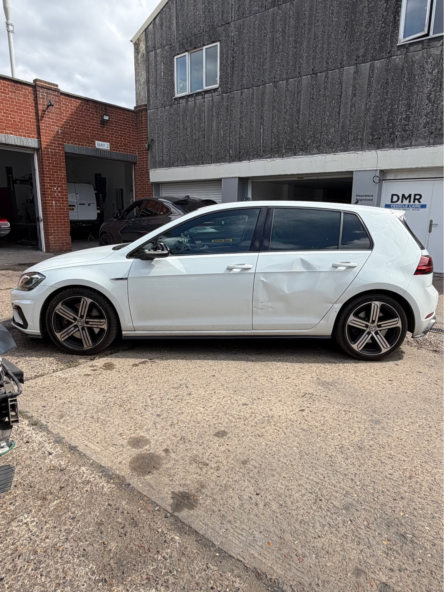 White car with side impact damage at the DMR workshop