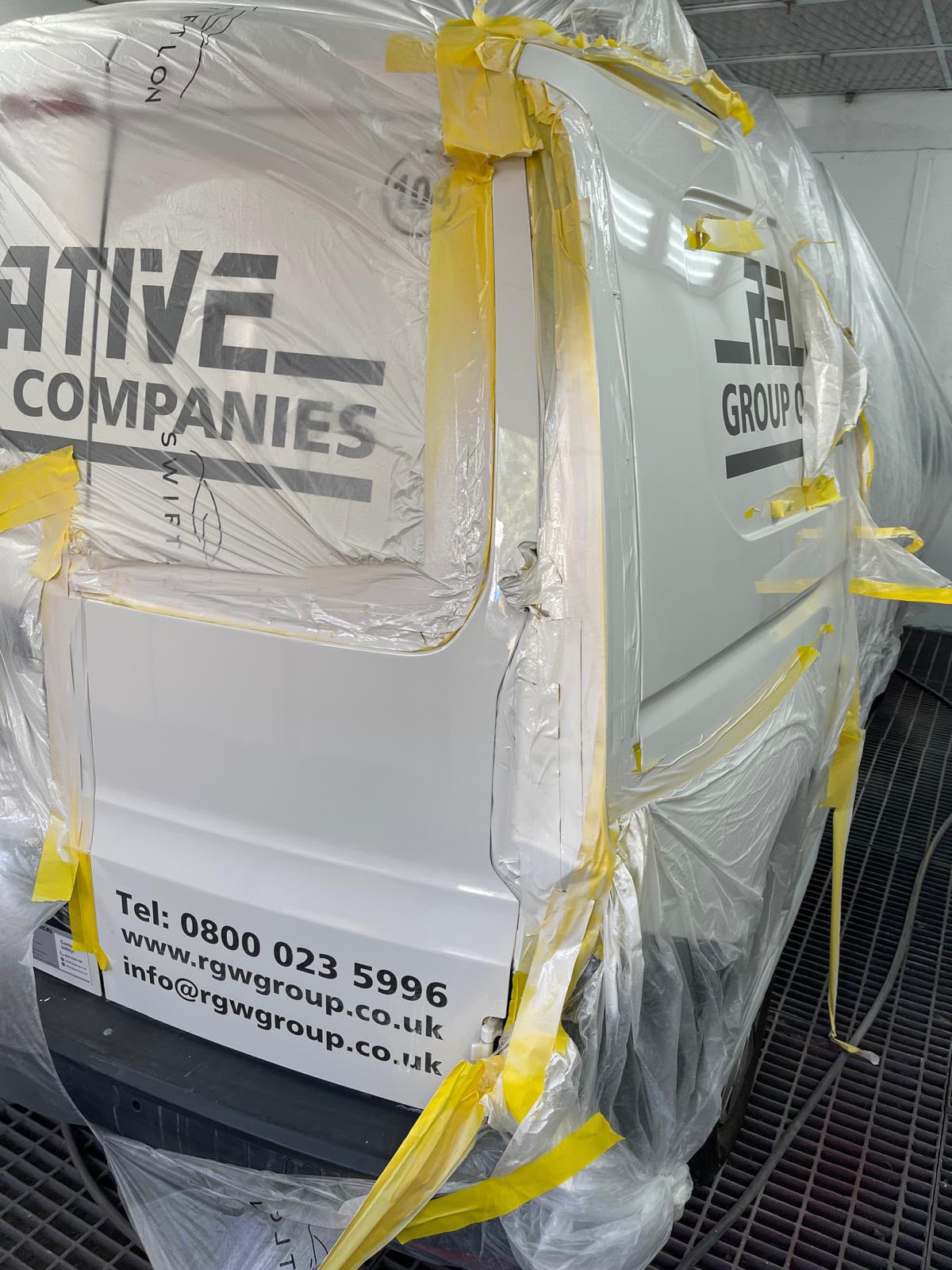 White van masked in the paint booth ready for refinishing